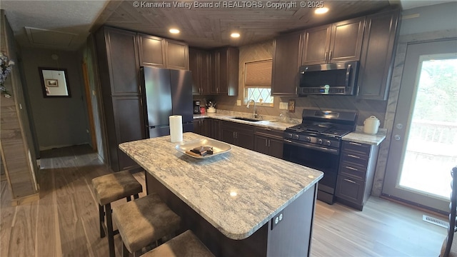 kitchen with a sink, appliances with stainless steel finishes, light wood-type flooring, and a healthy amount of sunlight