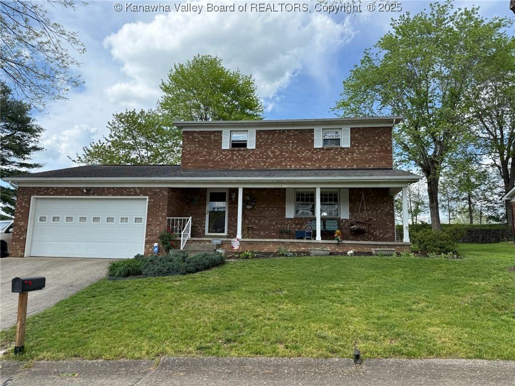 traditional-style home with a garage, a front lawn, brick siding, concrete driveway, and a porch