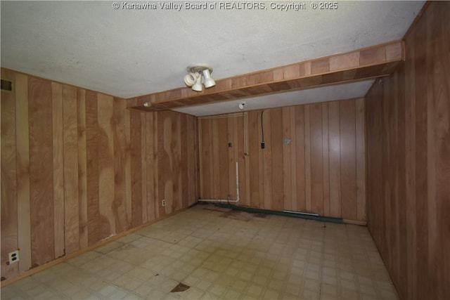 empty room featuring visible vents, wood walls, and light floors