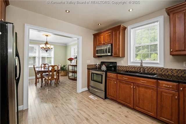 315 27th St SE, Charleston, WV 25304 - kitchen featuring an inviting chandelier, a sink, dark countertops, stainless steel appliances, and light wood-type flooring