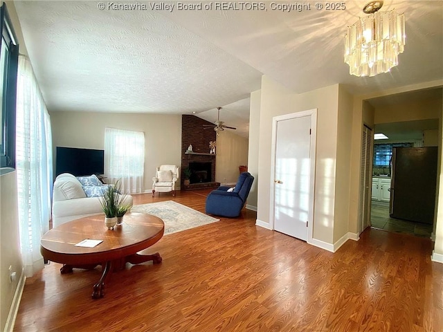 living room with a fireplace, lofted ceiling, baseboards, and wood finished floors