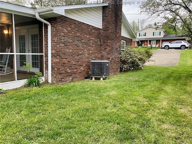 view of property exterior with central AC unit, a chimney, brick siding, and a lawn