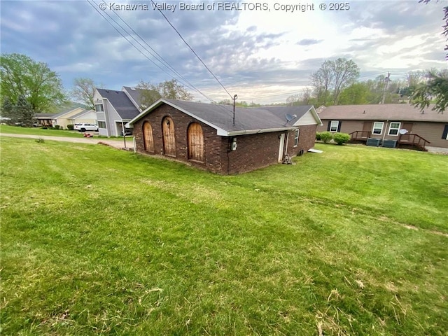 exterior space with brick siding, a deck, and a lawn