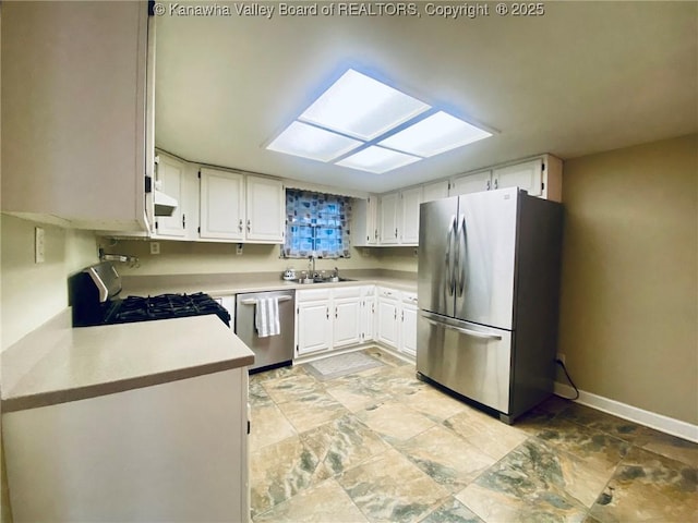 kitchen featuring a sink, stainless steel appliances, stone finish floor, light countertops, and white cabinets