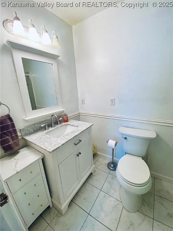bathroom with vanity, marble finish floor, wainscoting, and toilet