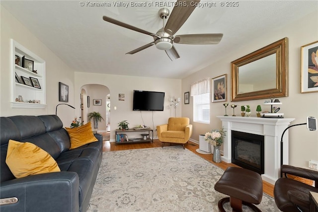 2258 Curtis Ave, Saint Albans, WV 25177 - living area featuring wood finished floors, built in features, ceiling fan, a glass covered fireplace, and arched walkways