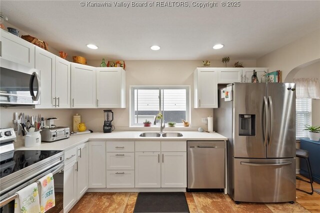 2258 Curtis Ave, Saint Albans, WV 25177 - kitchen featuring a sink, stainless steel appliances, light countertops, arched walkways, and white cabinets