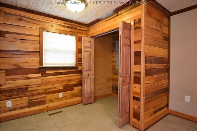 interior space featuring wooden ceiling, wood walls, and baseboards