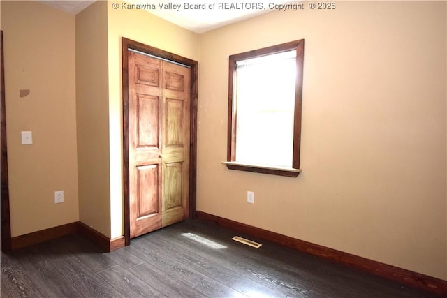 unfurnished bedroom with baseboards, a closet, visible vents, and dark wood-style floors