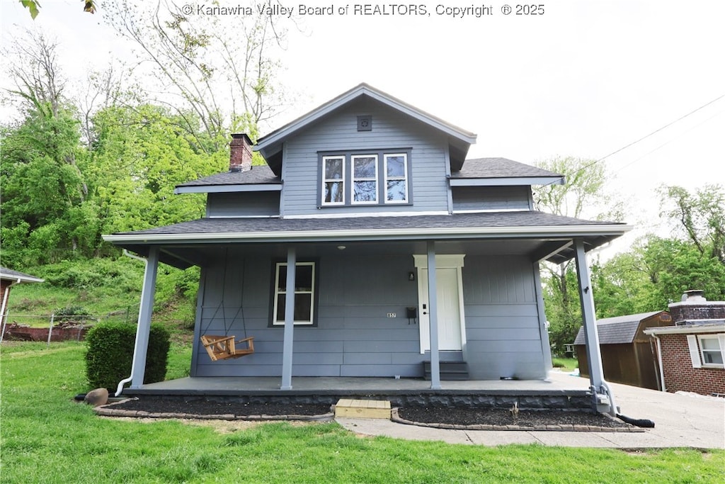 view of front of house with a chimney, a front yard, a porch, and a shingled roof