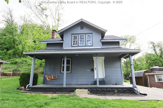 view of front of house with a chimney, a front yard, a porch, and a shingled roof