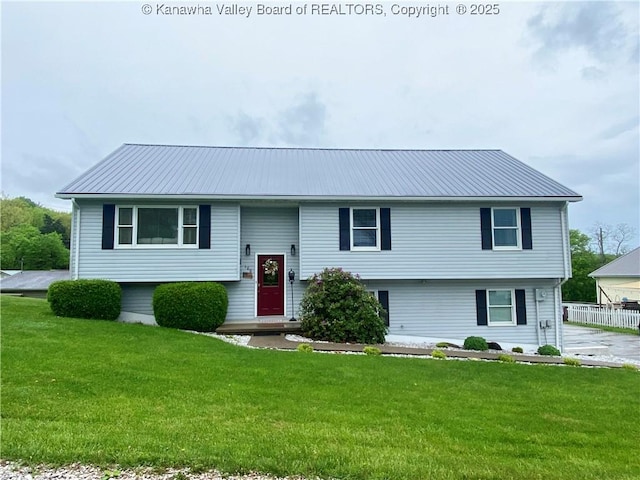 raised ranch featuring metal roof and a front lawn