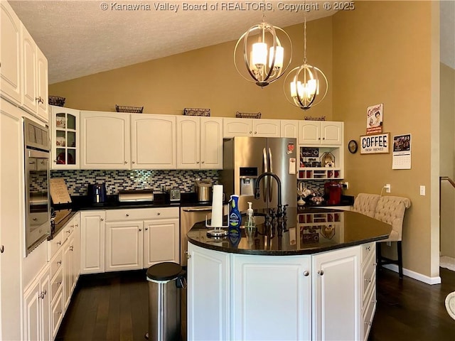kitchen with dark wood finished floors, dark countertops, appliances with stainless steel finishes, and vaulted ceiling