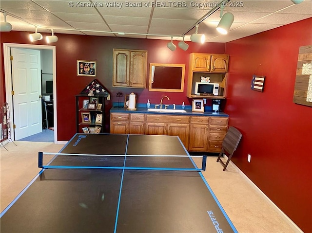 rec room featuring rail lighting, a drop ceiling, light carpet, and a sink