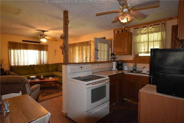 kitchen with a peninsula, open floor plan, light countertops, a ceiling fan, and white range with electric cooktop