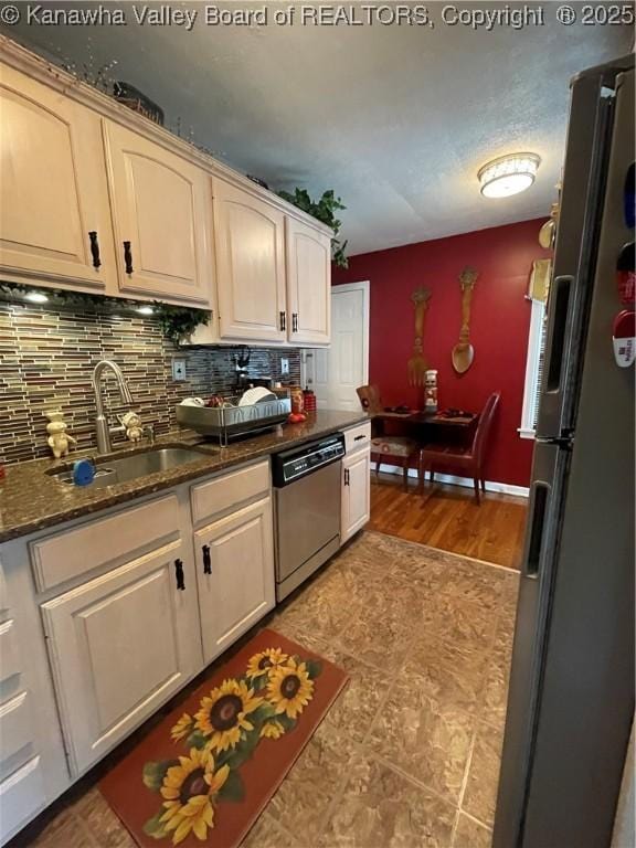 kitchen with dark stone counters, decorative backsplash, stainless steel appliances, and a sink