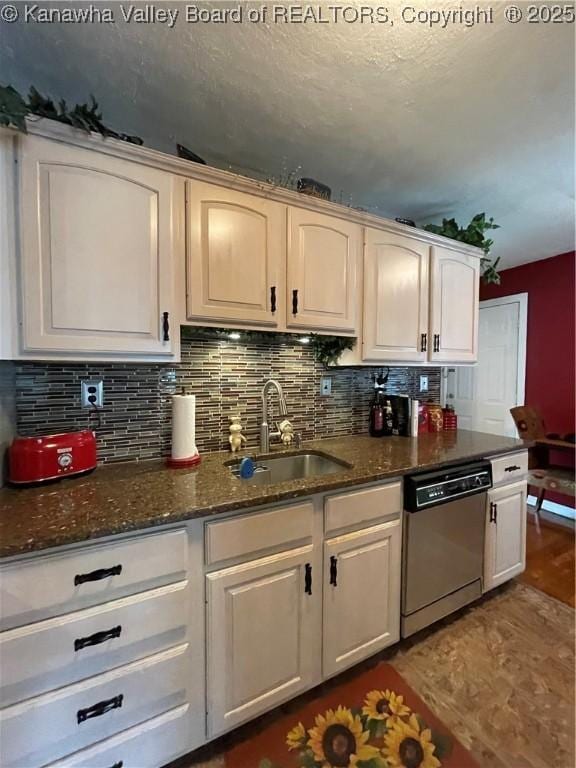 kitchen with dark stone counters, dishwasher, tasteful backsplash, and a sink