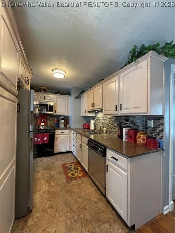 kitchen featuring a sink, dark countertops, stainless steel appliances, a textured ceiling, and decorative backsplash