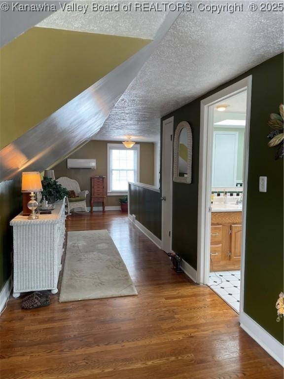 additional living space with a textured ceiling, baseboards, and wood finished floors