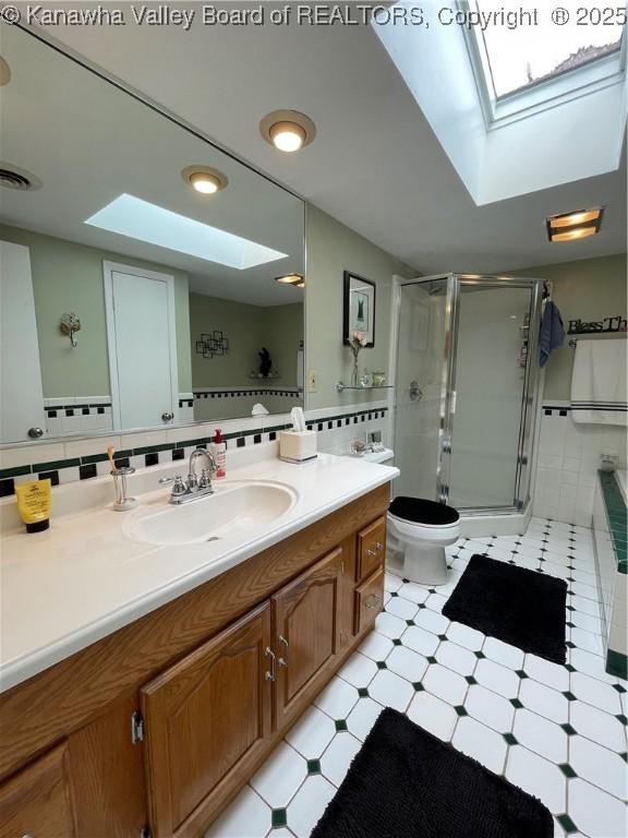bathroom with vanity, a shower stall, toilet, and a skylight
