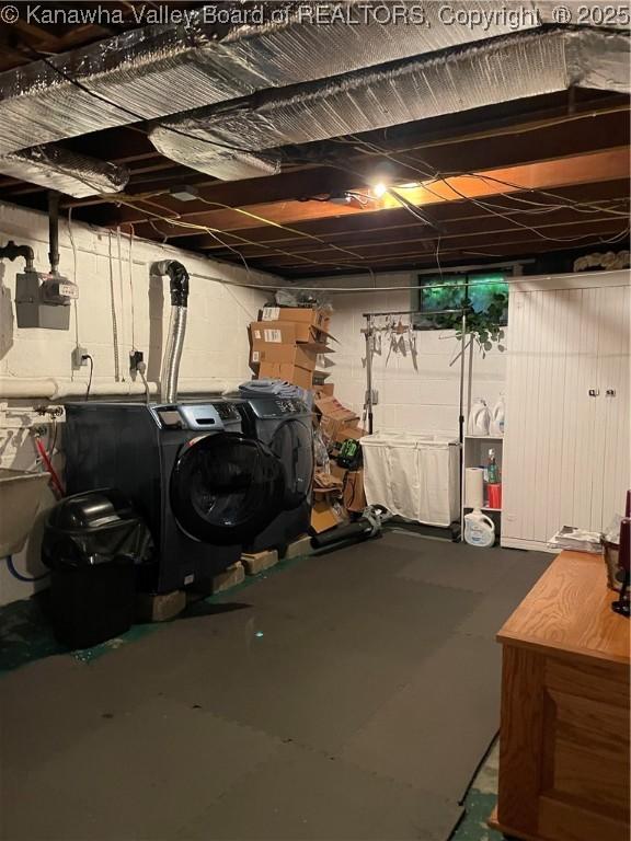 unfinished basement featuring a sink, separate washer and dryer, and concrete block wall