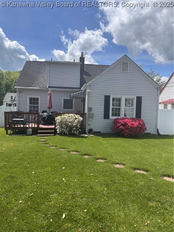 rear view of property featuring a deck, fence, and a lawn