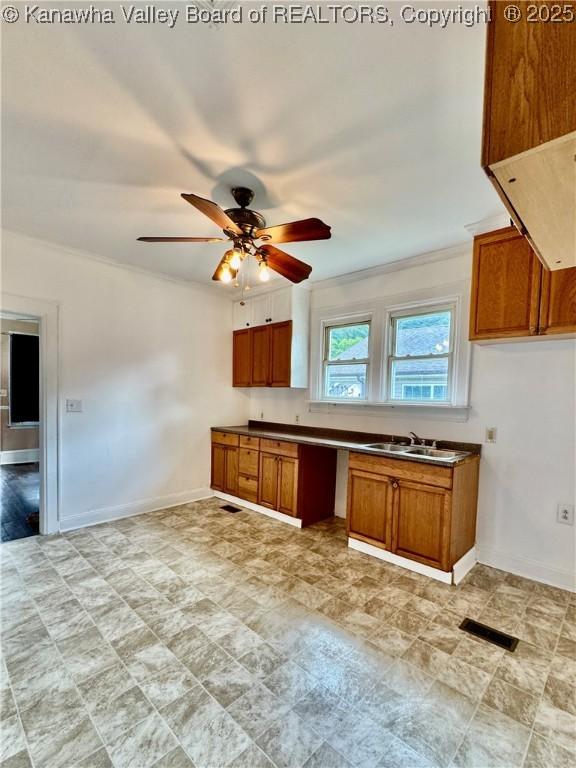 kitchen featuring a ceiling fan, brown cabinetry, visible vents, a sink, and dark countertops