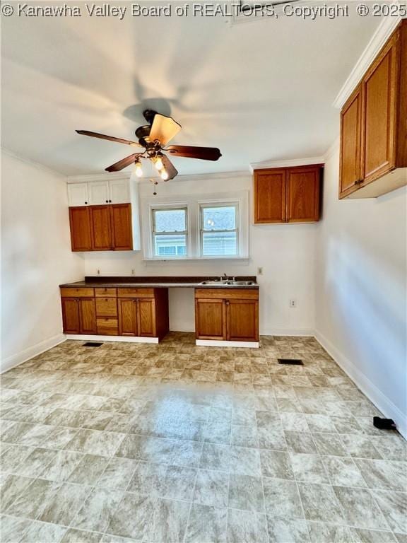 kitchen featuring brown cabinets, a sink, visible vents, baseboards, and ceiling fan