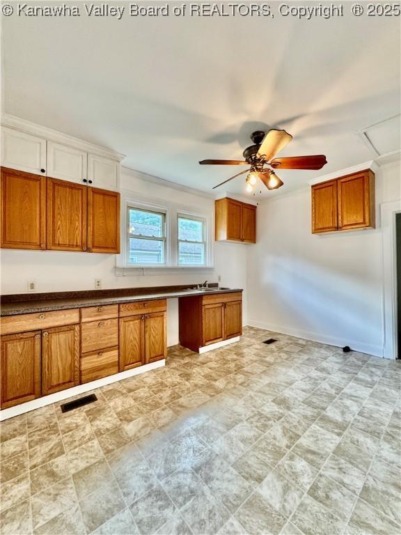 kitchen with crown molding, visible vents, brown cabinetry, and a ceiling fan