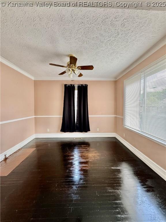 empty room featuring crown molding, baseboards, a ceiling fan, and wood-type flooring