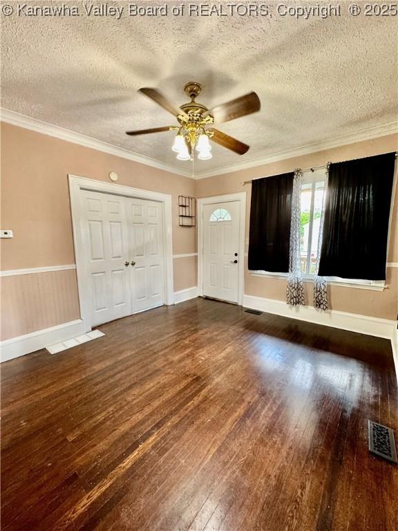 entryway featuring a textured ceiling, visible vents, ceiling fan, wood-type flooring, and baseboards