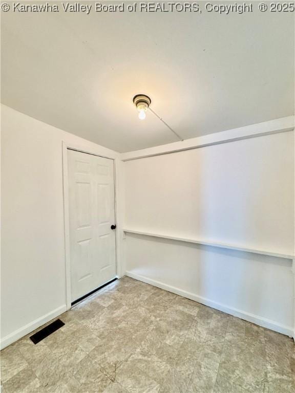 empty room with vaulted ceiling, baseboards, and visible vents