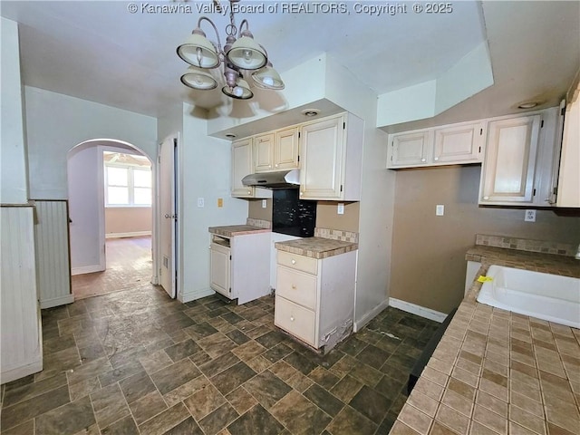 728 98th St, Charleston, WV 25315 - kitchen featuring a sink, stone finish floor, baseboards, arched walkways, and under cabinet range hood