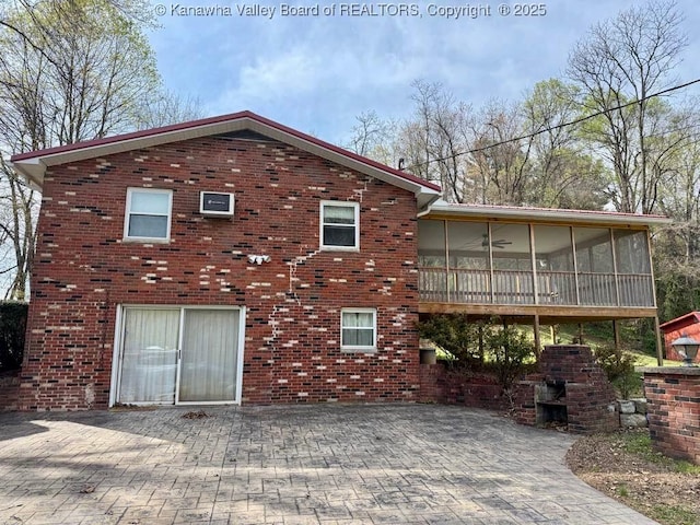 rear view of house featuring brick siding and a sunroom