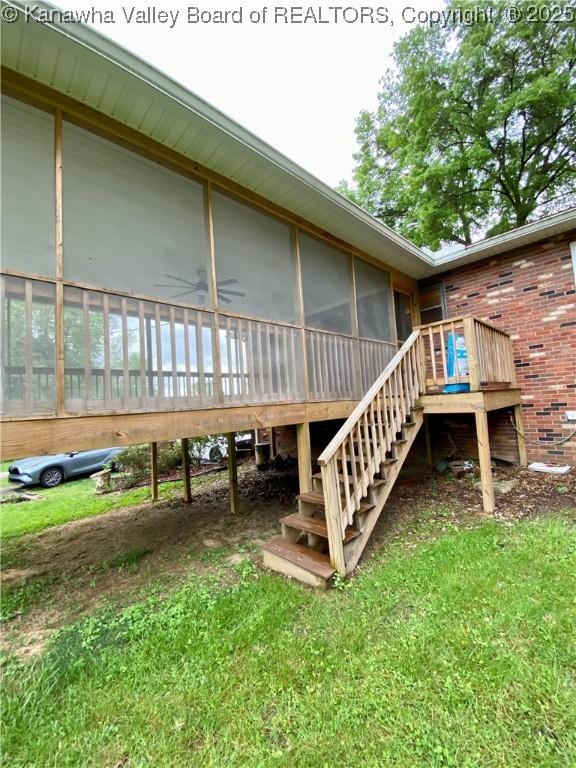 exterior space with a lawn, stairs, brick siding, and a sunroom