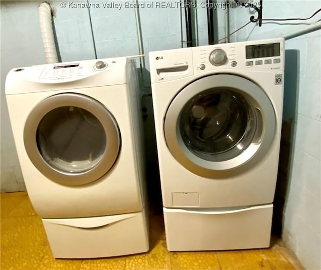 washroom with laundry area, independent washer and dryer, and concrete block wall
