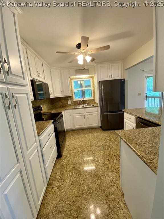kitchen with a sink, dark stone counters, black appliances, a ceiling fan, and white cabinets