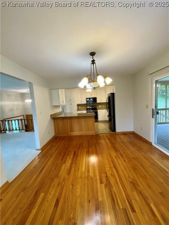 unfurnished dining area featuring baseboards, a chandelier, and wood finished floors