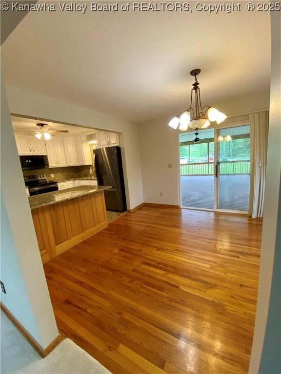 kitchen featuring freestanding refrigerator, light wood-style flooring, baseboards, stainless steel electric range, and tasteful backsplash