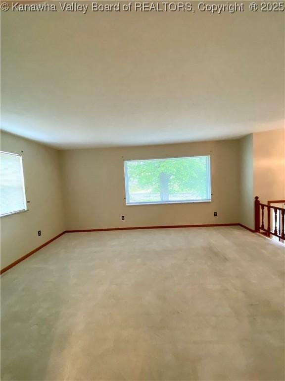 empty room with baseboards, light carpet, and a healthy amount of sunlight