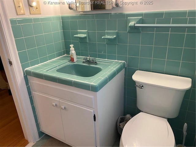 1407 Longridge Rd, Charleston, WV 25314 - bathroom featuring tile walls, vanity, toilet, wood finished floors, and a wainscoted wall
