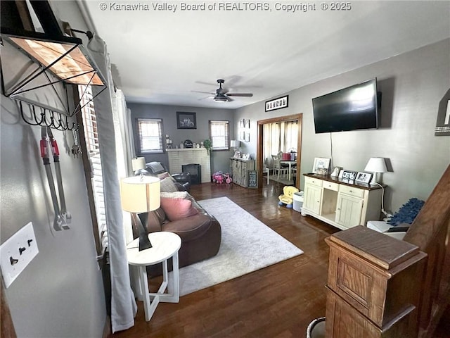 living room featuring a ceiling fan, a fireplace, and dark wood-style floors