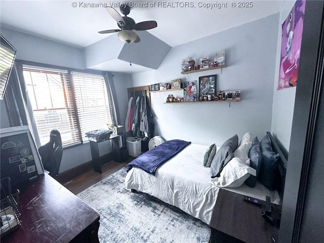 bedroom featuring wood finished floors, ceiling fan, vaulted ceiling, and baseboards