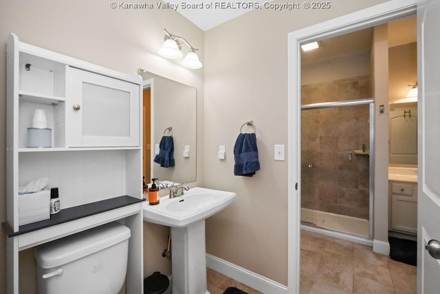 full bathroom featuring a stall shower, toilet, tile patterned flooring, baseboards, and a sink