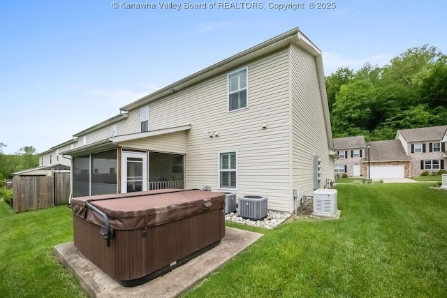 back of property featuring a hot tub, central air condition unit, and a sunroom
