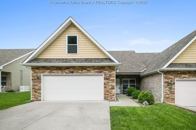 view of front of house with roof with shingles, stone siding, a garage, and a front lawn