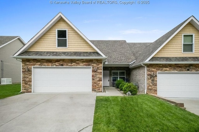 view of front of home featuring stone siding, roof with shingles, a front yard, and driveway