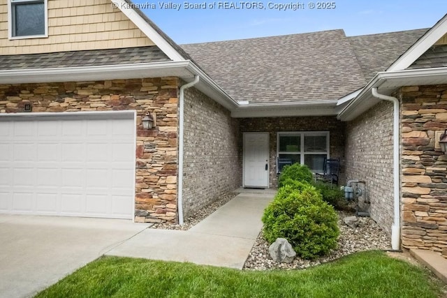entrance to property featuring roof with shingles, stone siding, and a garage