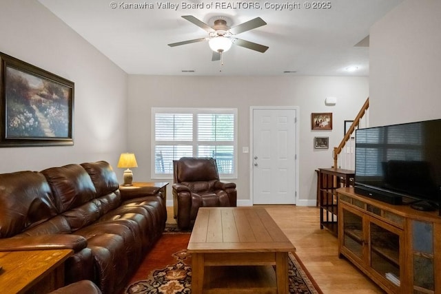 living room with wood finished floors, stairs, a ceiling fan, and baseboards