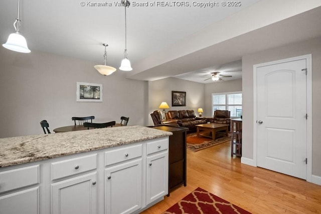 kitchen featuring white cabinets, a ceiling fan, light wood-style flooring, and pendant lighting